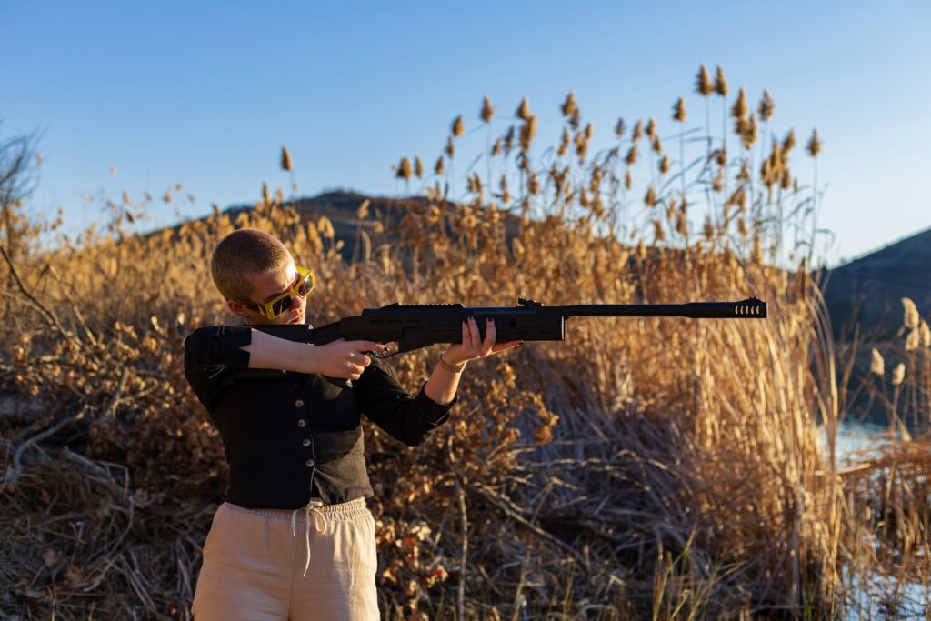 a man holding a rifle in front of a body of water
