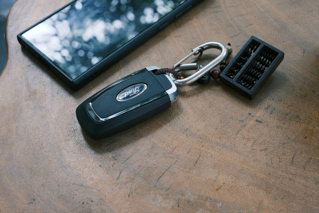 Car key, phone, and keychain on a wooden surface.