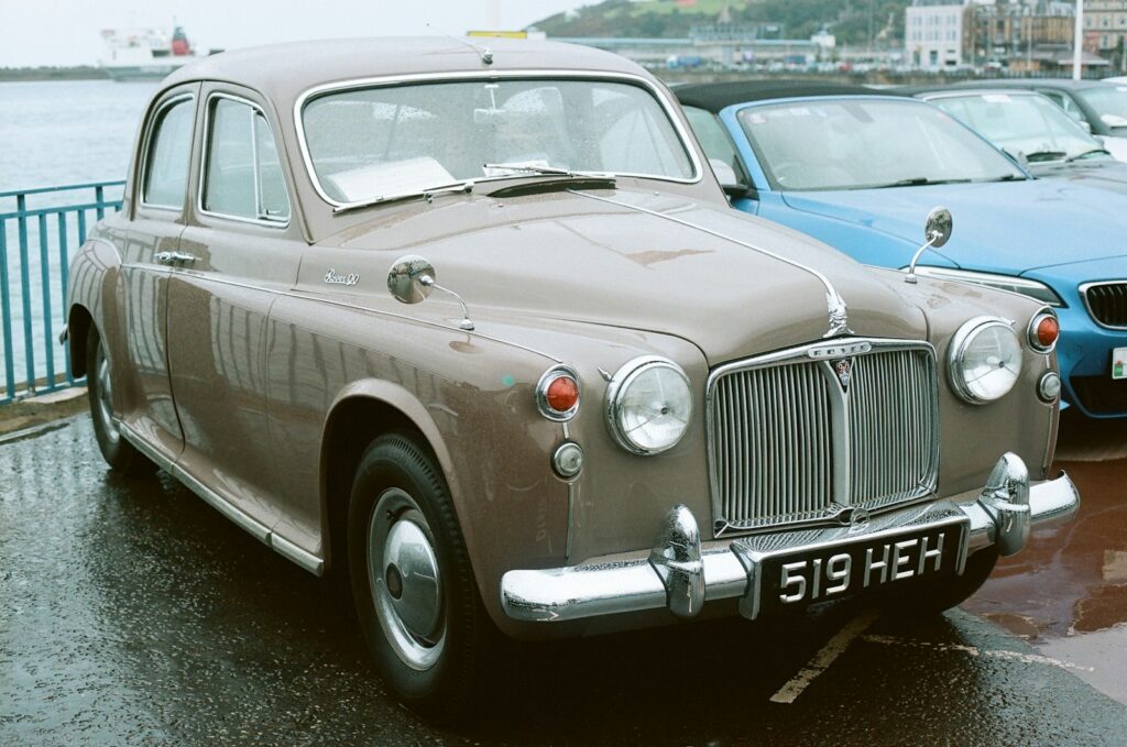 A vintage brown sedan parked by the water.