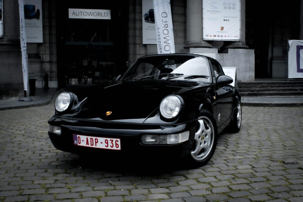 black porsche 911 parked on gray brick floor