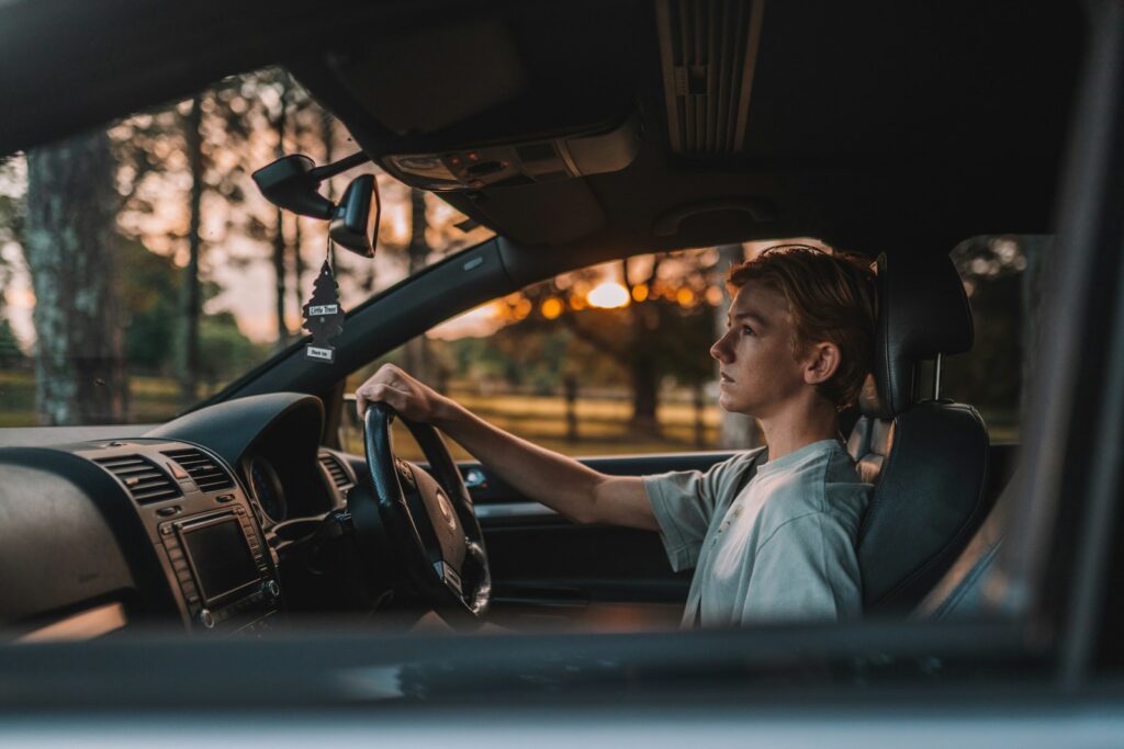 a man sitting in a car with his hand on the steering wheel