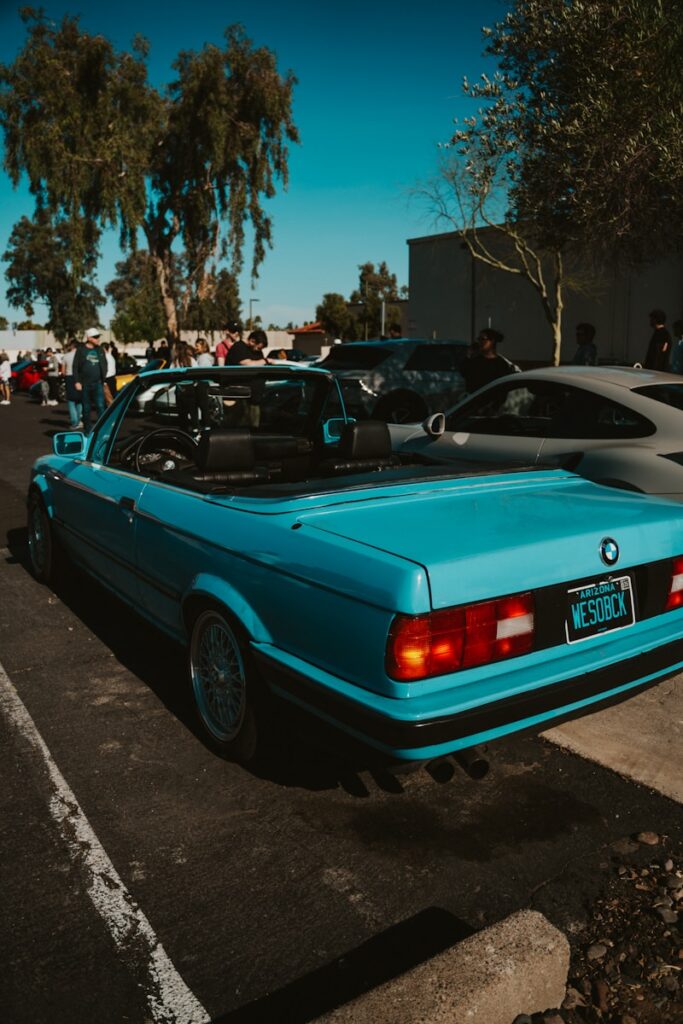 A blue BMW convertible parks in a lot.