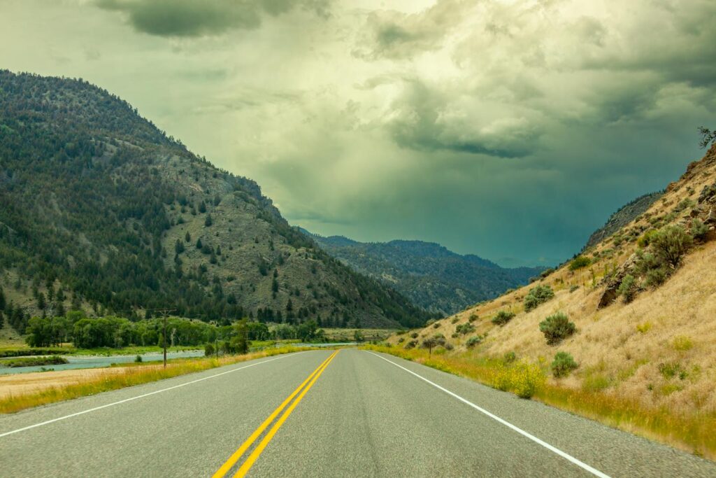 Scenic highway through Wyoming's mountainous countryside under dramatic cloudy skies.