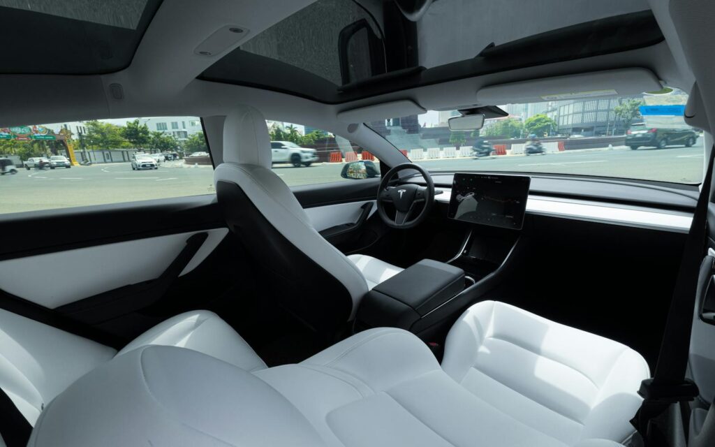 Elegant interior of an electric car featuring luxurious white leather seats and a panoramic view.