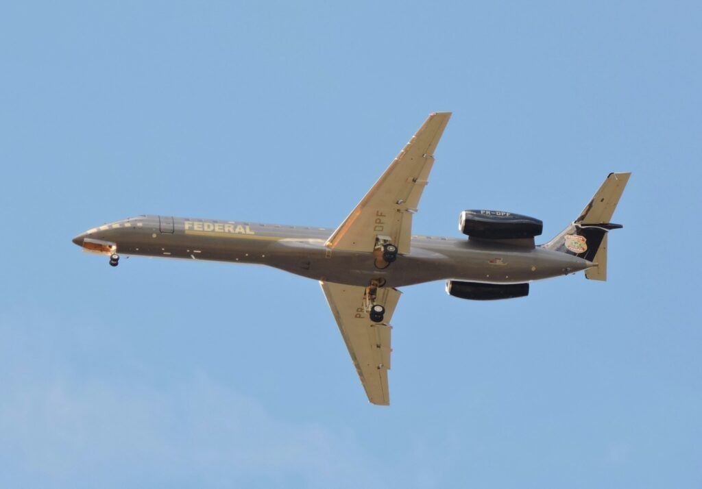 An airplane flies against a blue sky.