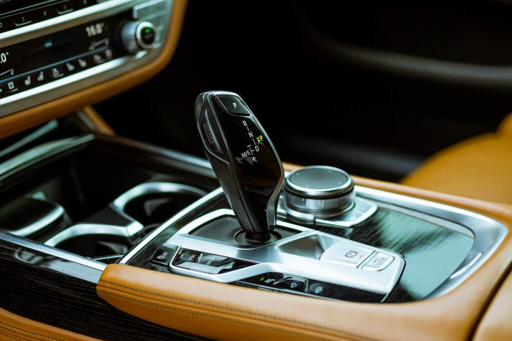 Close-up of a luxury car gear stick and dashboard featuring leather and modern design.