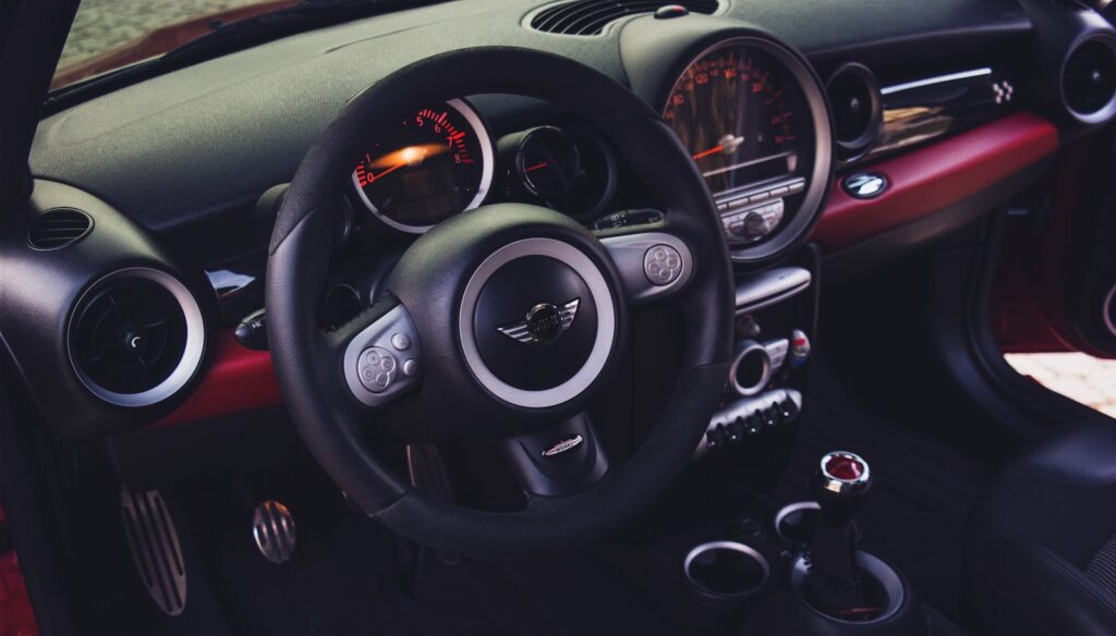 Interior of a Mini Cooper featuring the dashboard, steering wheel, and speedometer.