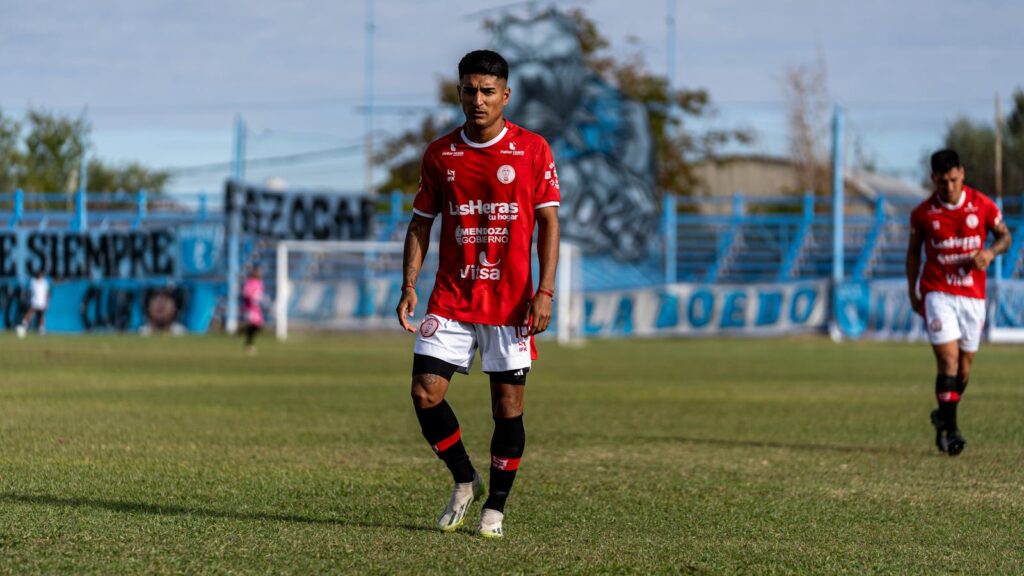 Two soccer players in red jerseys on a grassy field during a match.