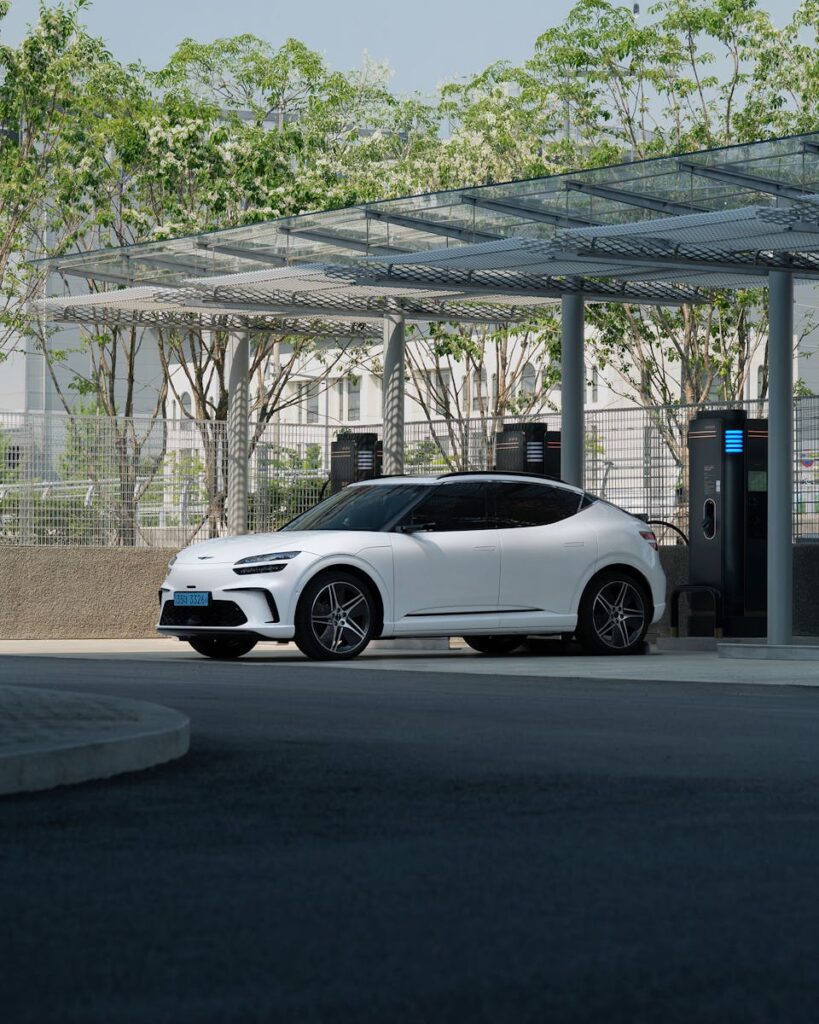A white electric SUV charging at an outdoor station under clear blue skies.