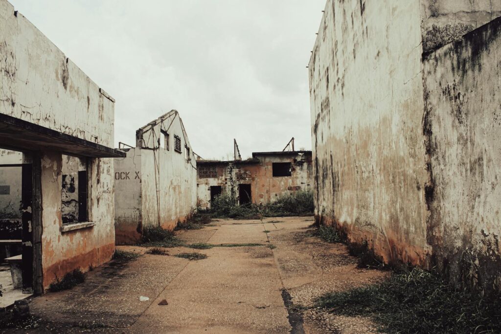 Derelict industrial complex with weathered walls and overgrown path, capturing decay and urban exploration.