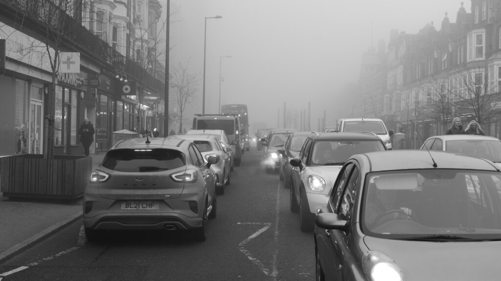 Cars stuck in traffic on a foggy street.