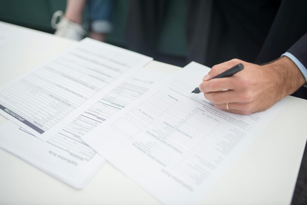 Close-up of a hand signing insurance documents in an office setting.