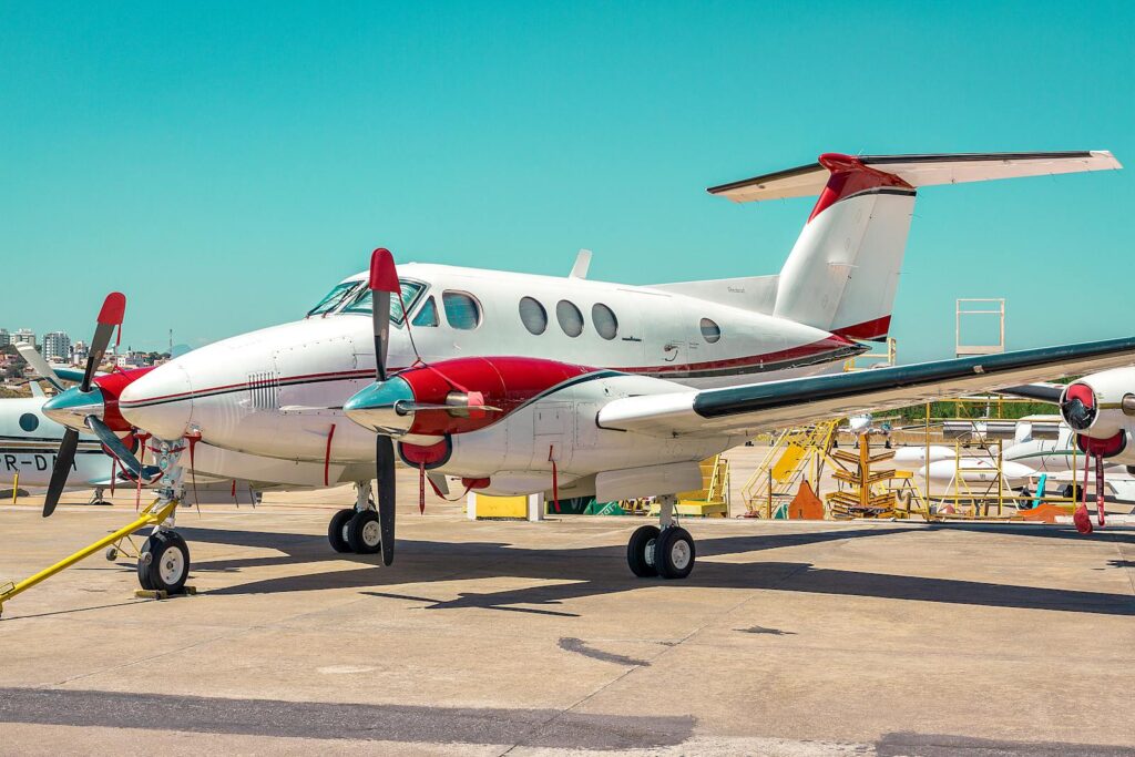 A white and red private jet parked on a sunny airstrip in Brazil under a clear blue sky.