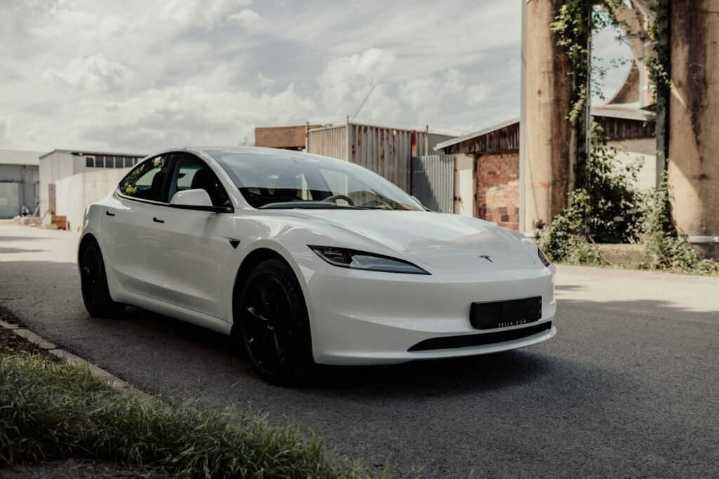 A white car driving down a street next to a building