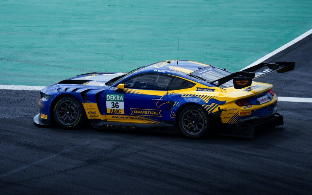 A ford mustang race car speeds on a track.