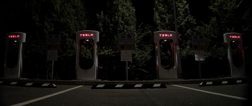 a row of gas pumps in a parking lot at night