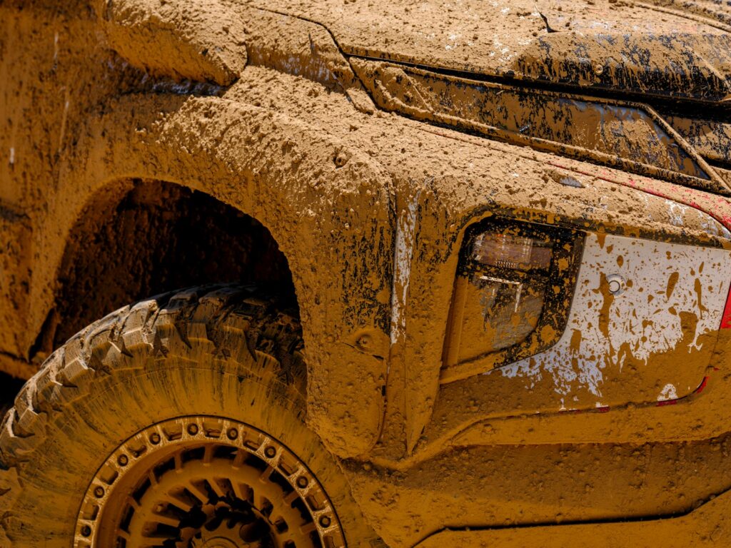 Mud-covered off-road vehicle with rugged tires.