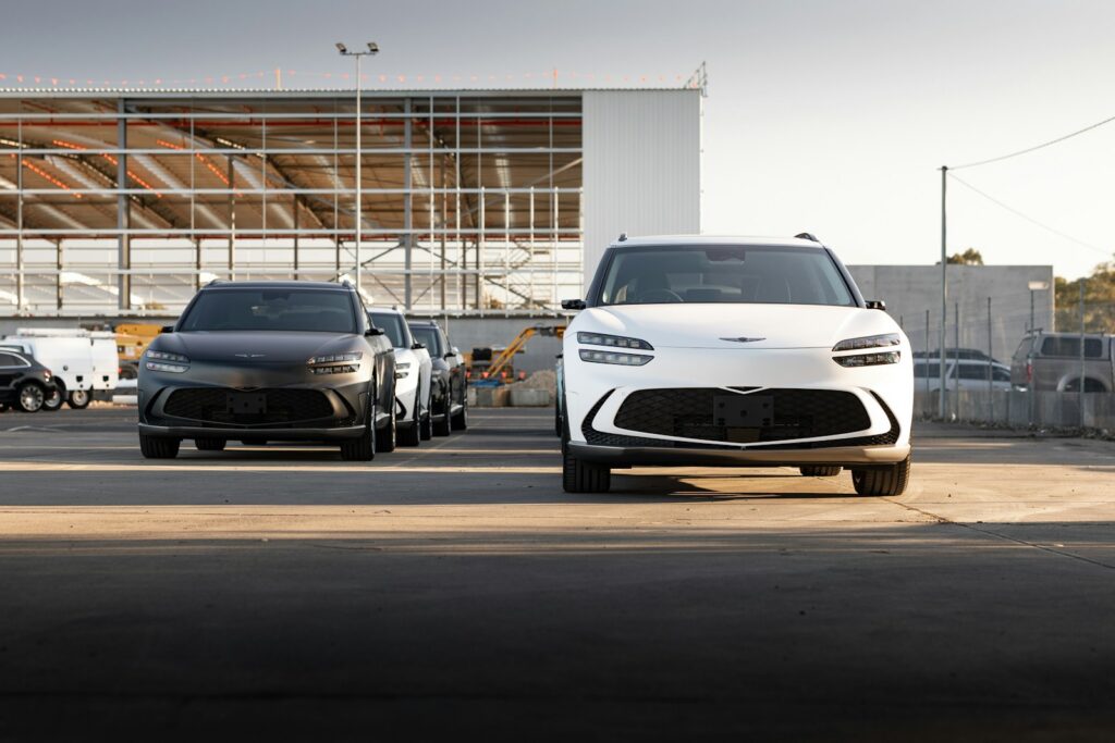 Two electric suvs are parked in front of a building.