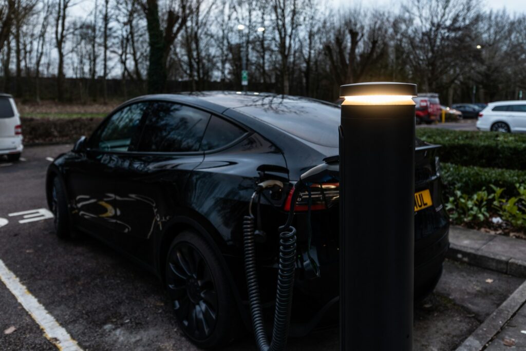 Black electric car charging at an outdoor station.