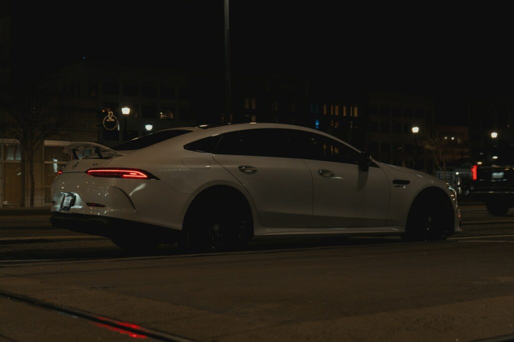 A white car driving down a street at night