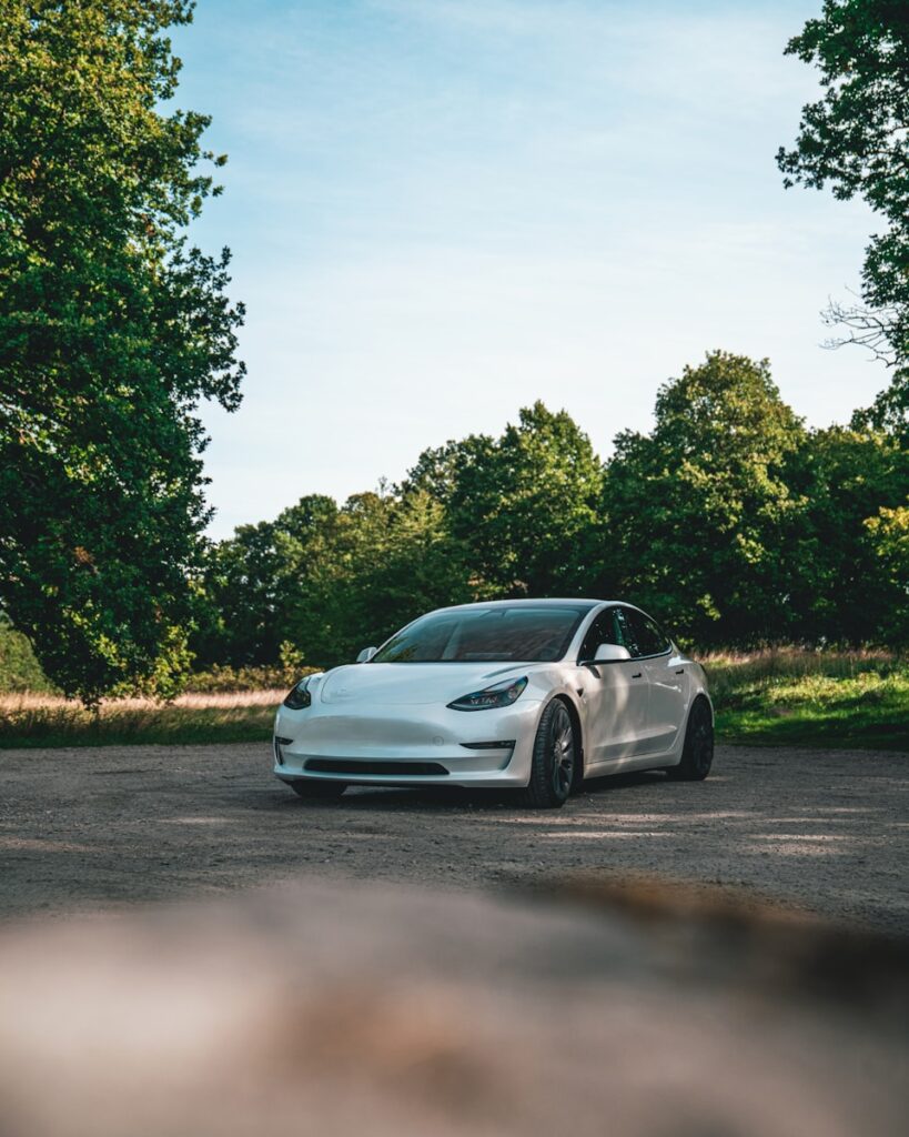 a white car parked in a parking lot next to trees