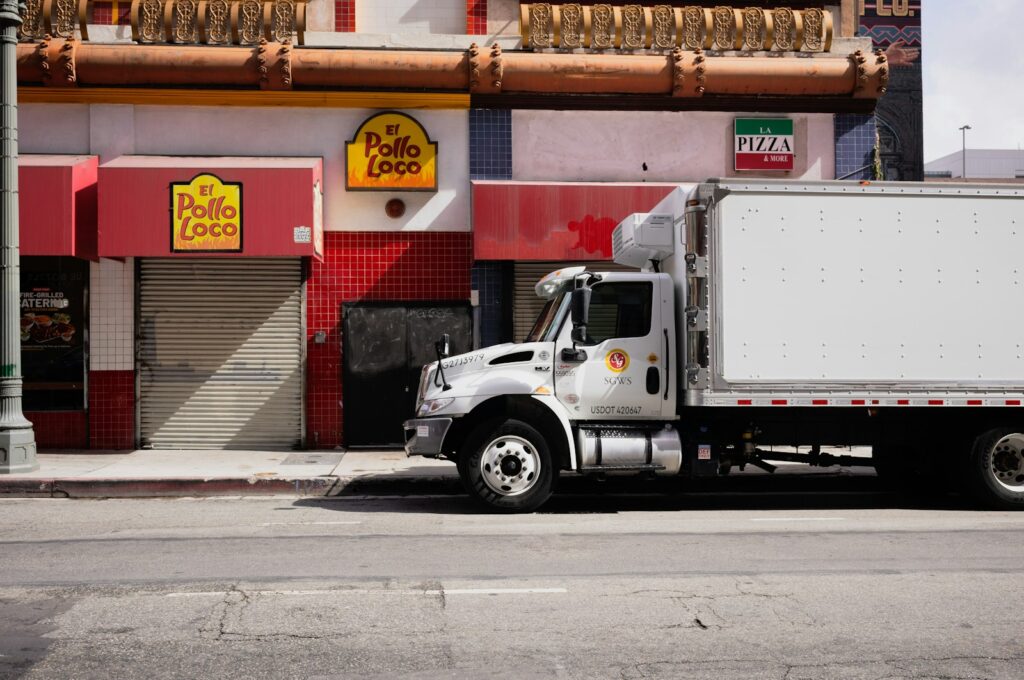 White truck parked on city street near businesses.