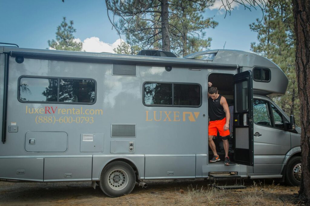 A man steps out of a luxury RV, parked at a scenic campsite in Big Bear, CA.