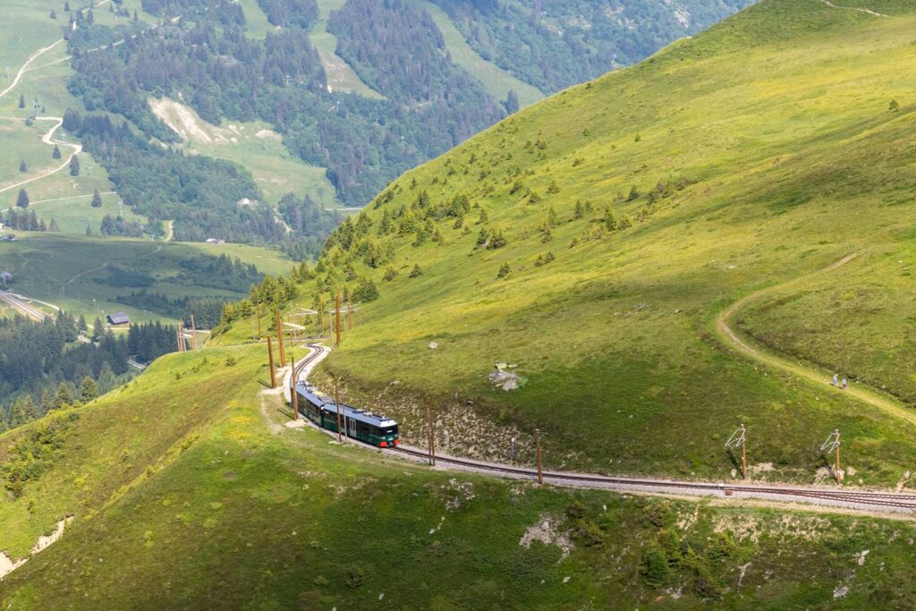 Explore scenic mountain views with a train traveling through lush green hills.