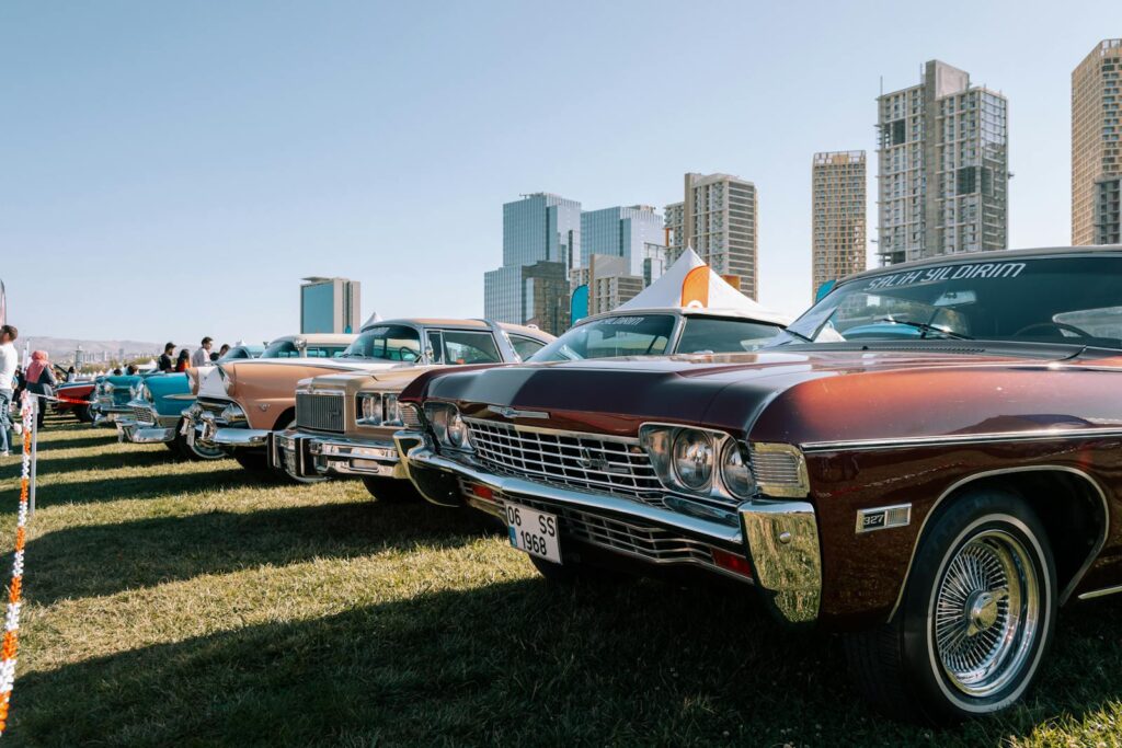 Vintage cars displayed outdoors against a city skyline, highlighting classic automotive design.