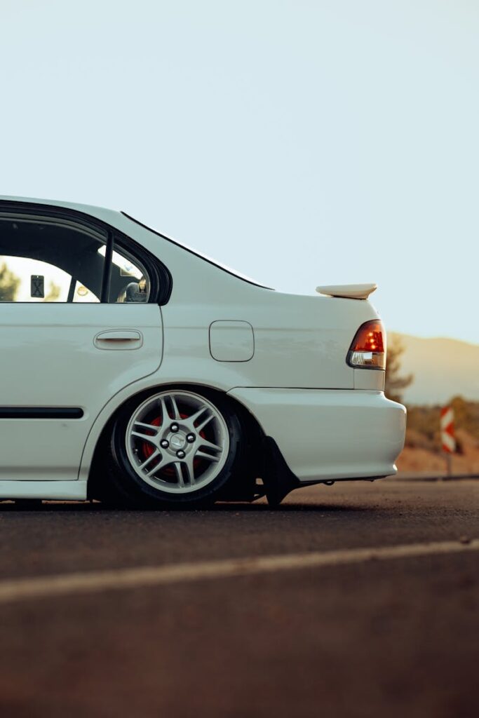 A stylish white sedan parked on a quiet road, highlighting the vehicle's sleek design and smooth asphalt surface.