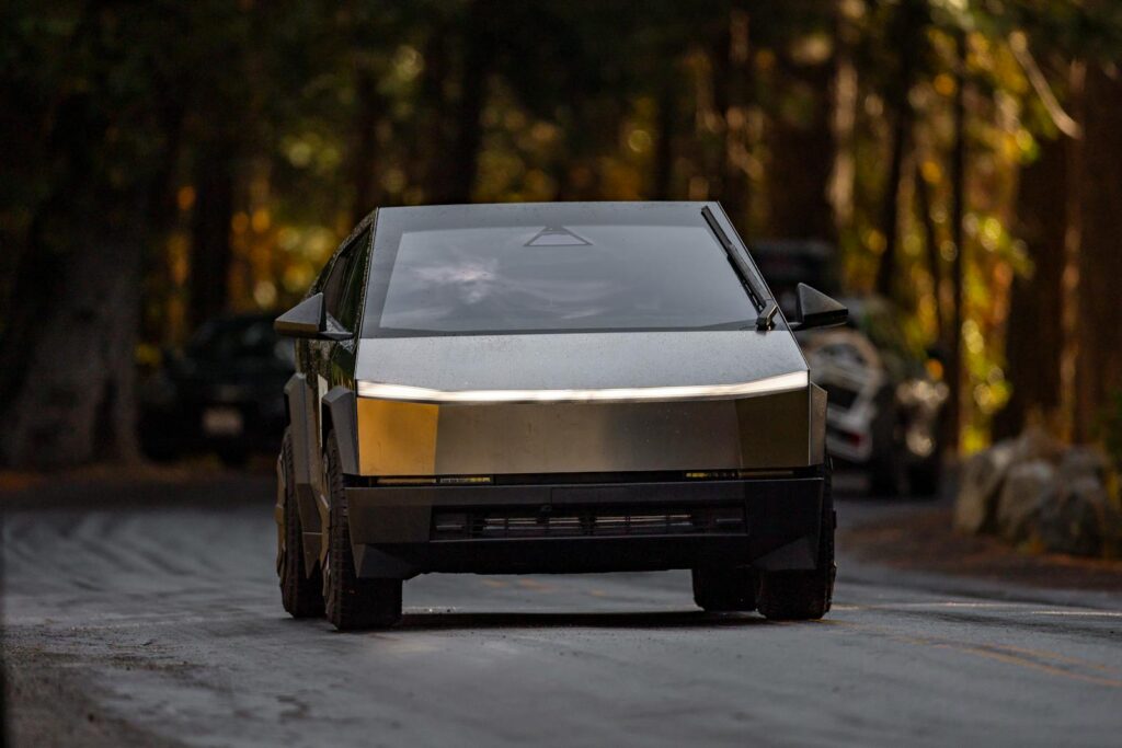 Sleek electric truck driving through a tranquil forest setting with modern design.