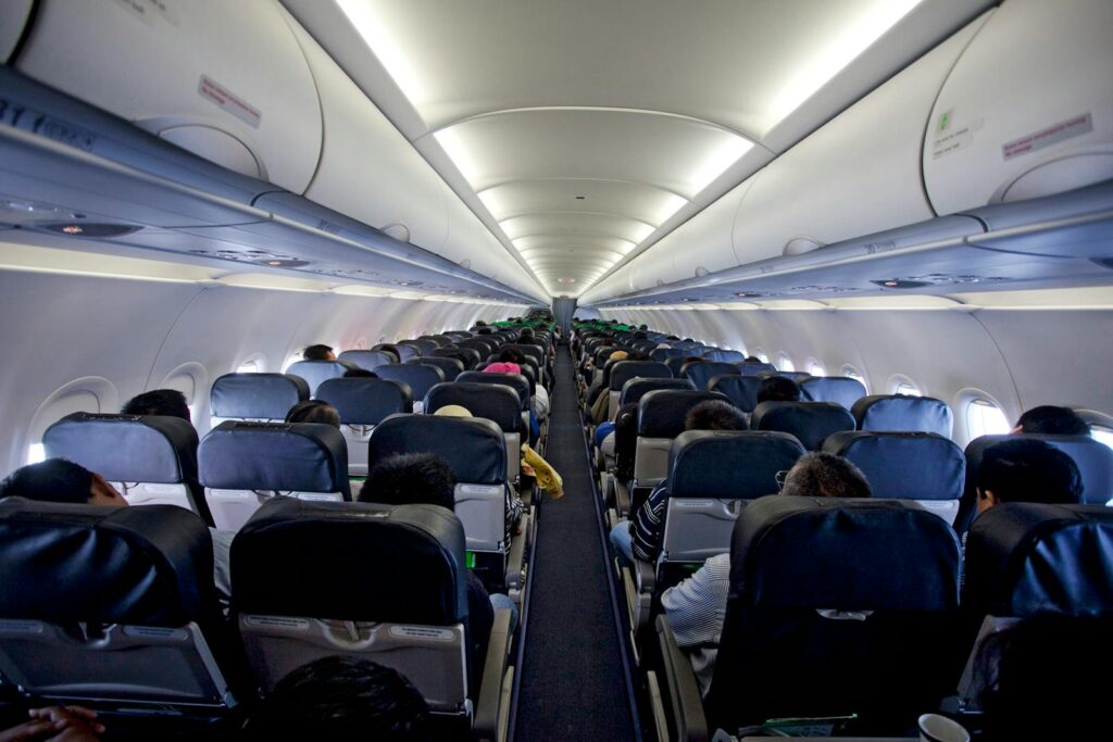 Interior view of a fully occupied airplane cabin during flight showcasing passengers and overhead compartments.