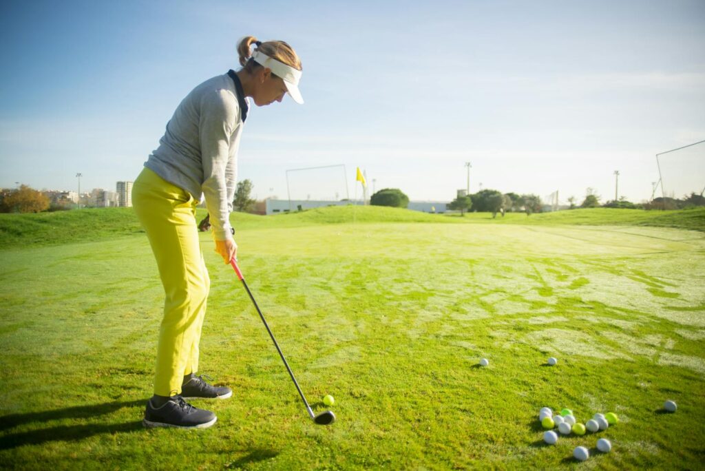Female golfer practicing her swing on a sunny day in Portugal with vibrant green grass.