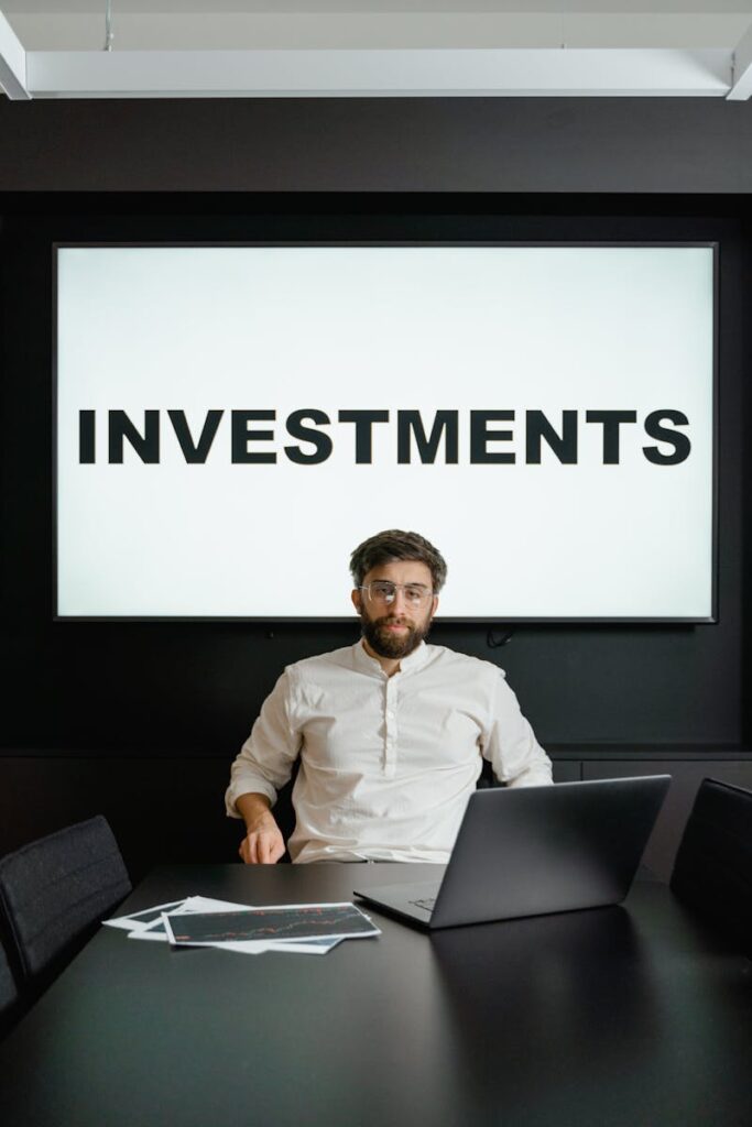 Man in office with investment presentation on screen and papers on table.