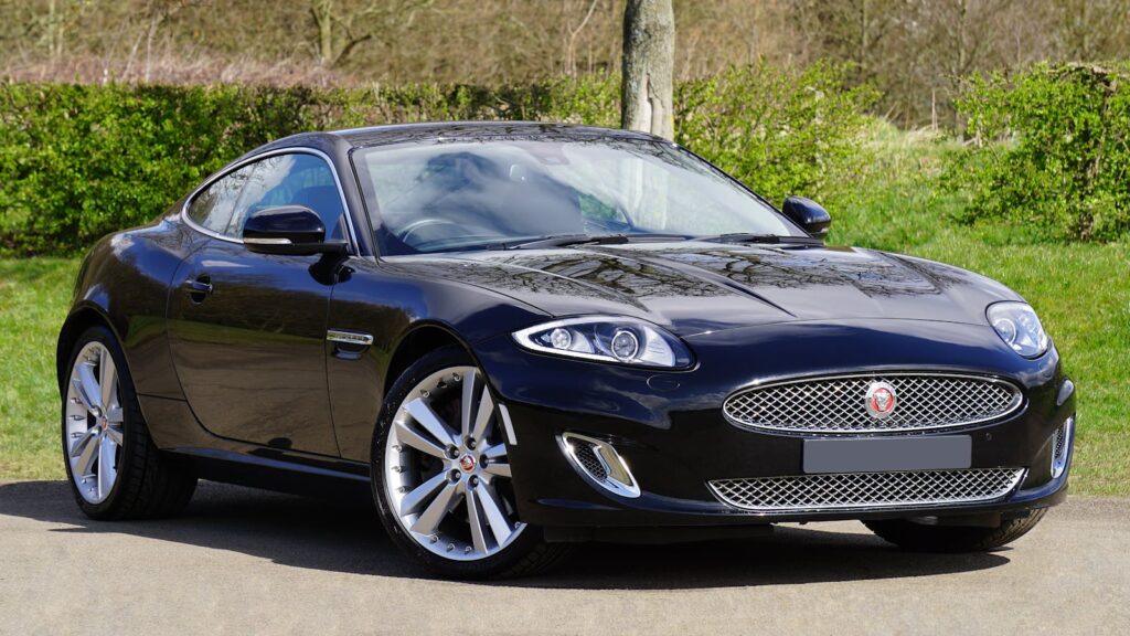 Stylish black Jaguar XK coupe with shiny wheels and classic design parked outdoors.