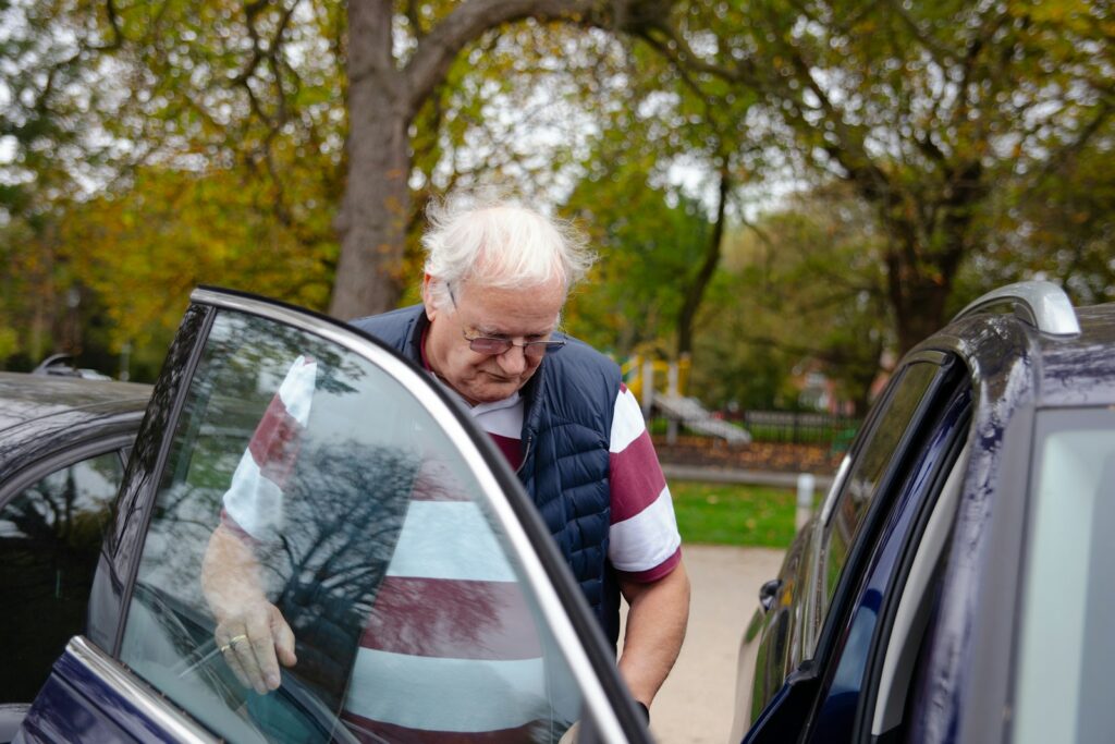 Elderly man getting into a car