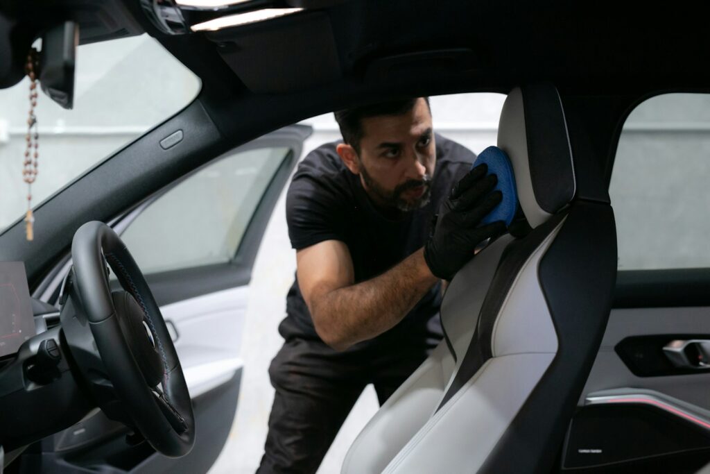 A man cleans a car seat inside the vehicle.
