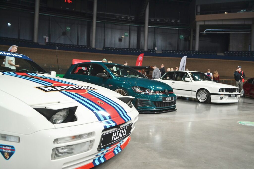 Three cars displayed at an indoor event.