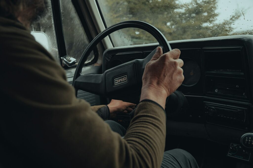 a man driving a truck with his hands on the steering wheel
