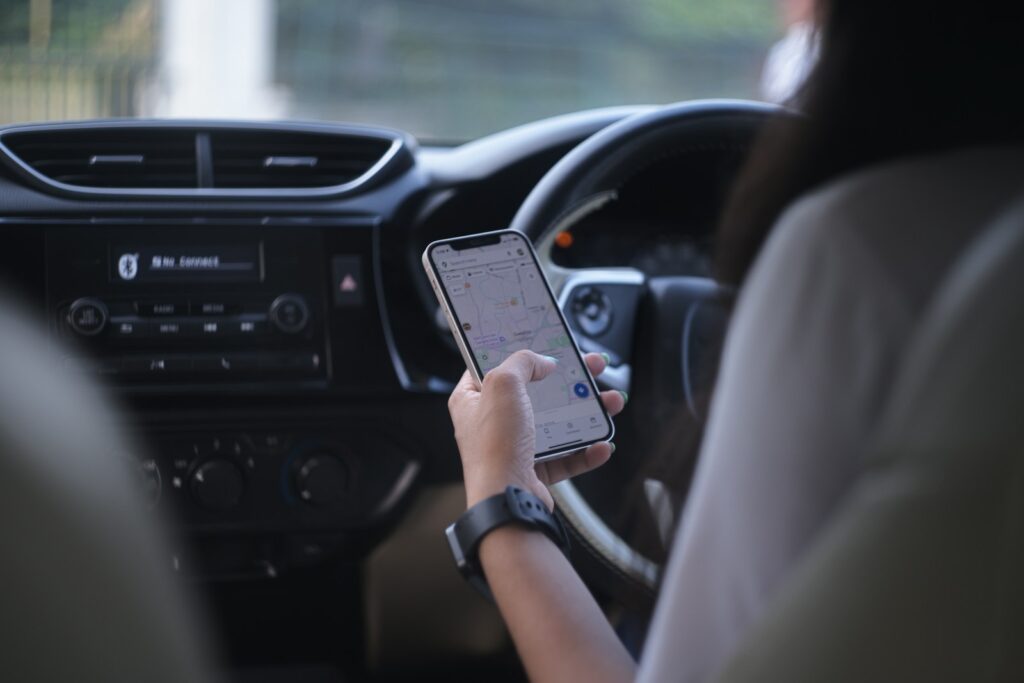 A woman holding a cell phone while driving a car