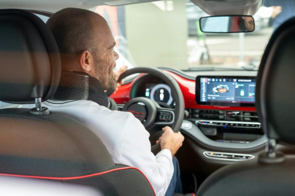 A man driving a car with a steering wheel