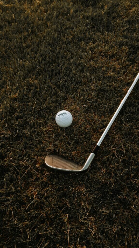 A golf ball and a golf club laying on the grass