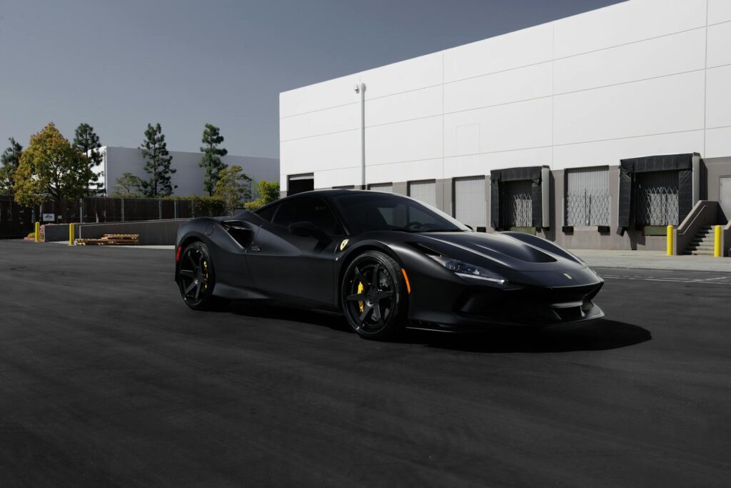 A striking black Ferrari F8 Tributo parked in an industrial area, showcasing luxury and style.