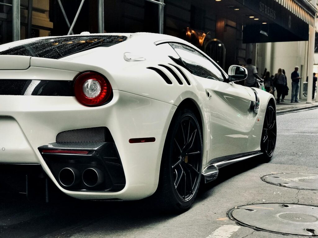 Sleek white sports car parked on an urban New York street with people in the background.