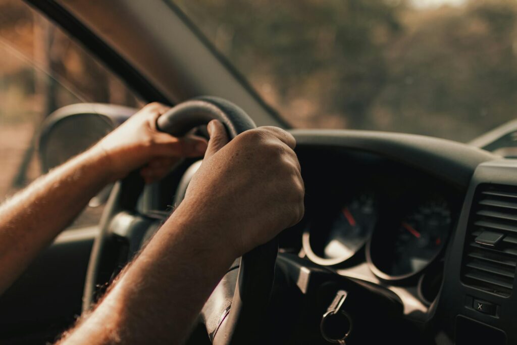 Driver's hands on a steering wheel inside a vehicle, focusing on the act of driving.