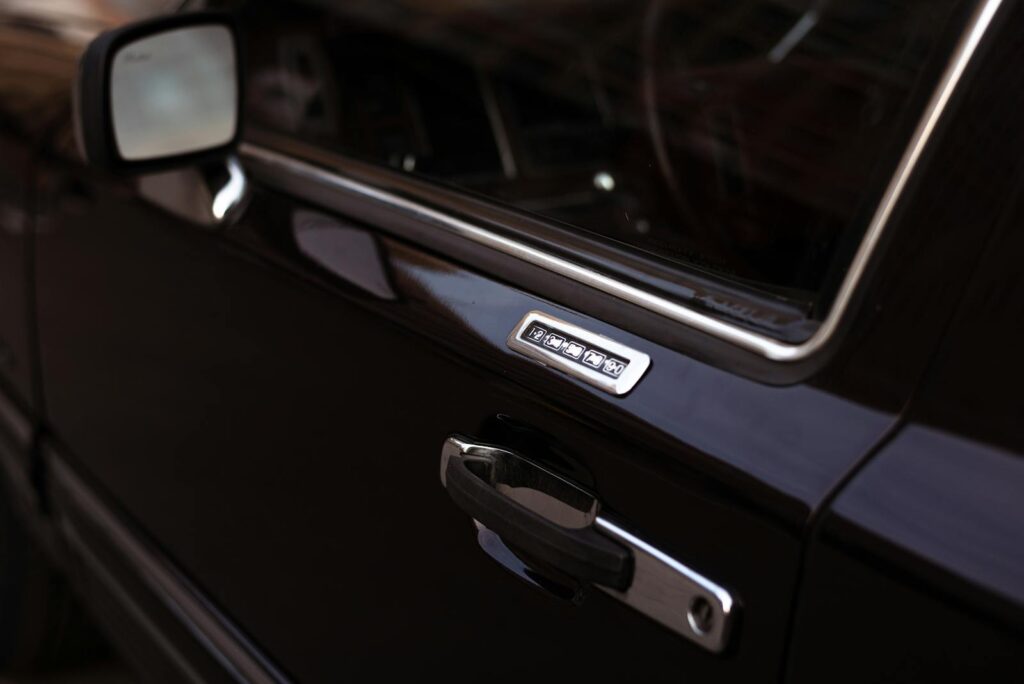 Close-up of a classic black car door with keypad lock, showcasing metallic details.