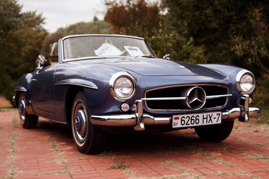 A vintage Mercedes-Benz convertible car parked outdoors on a brick path.