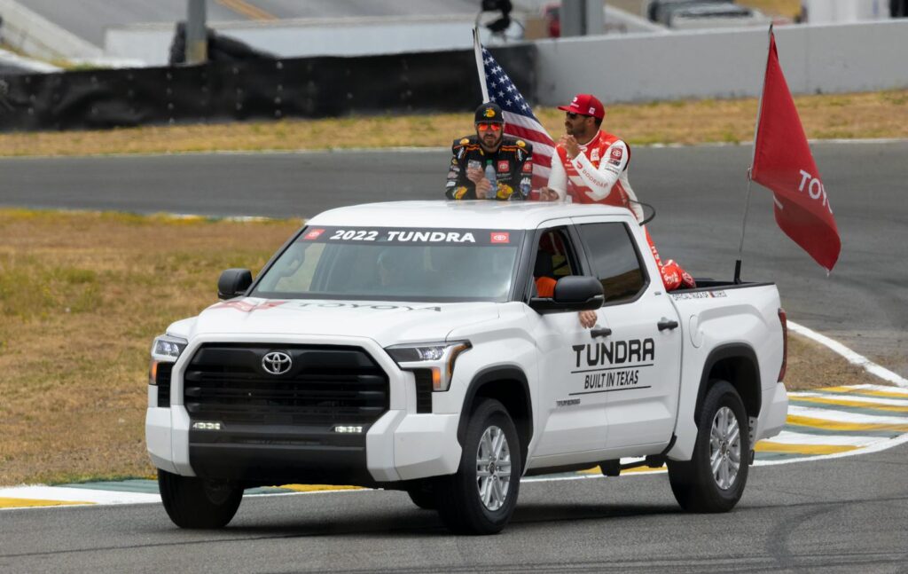 A Toyota Tundra showcasing at a racing event with drivers and flags. Perfect for motorsport enthusiasts.