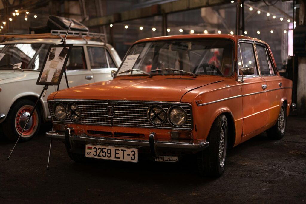 Classic orange sedan showcased in an indoor vintage car exhibition setting. Nostalgic automotive appeal.