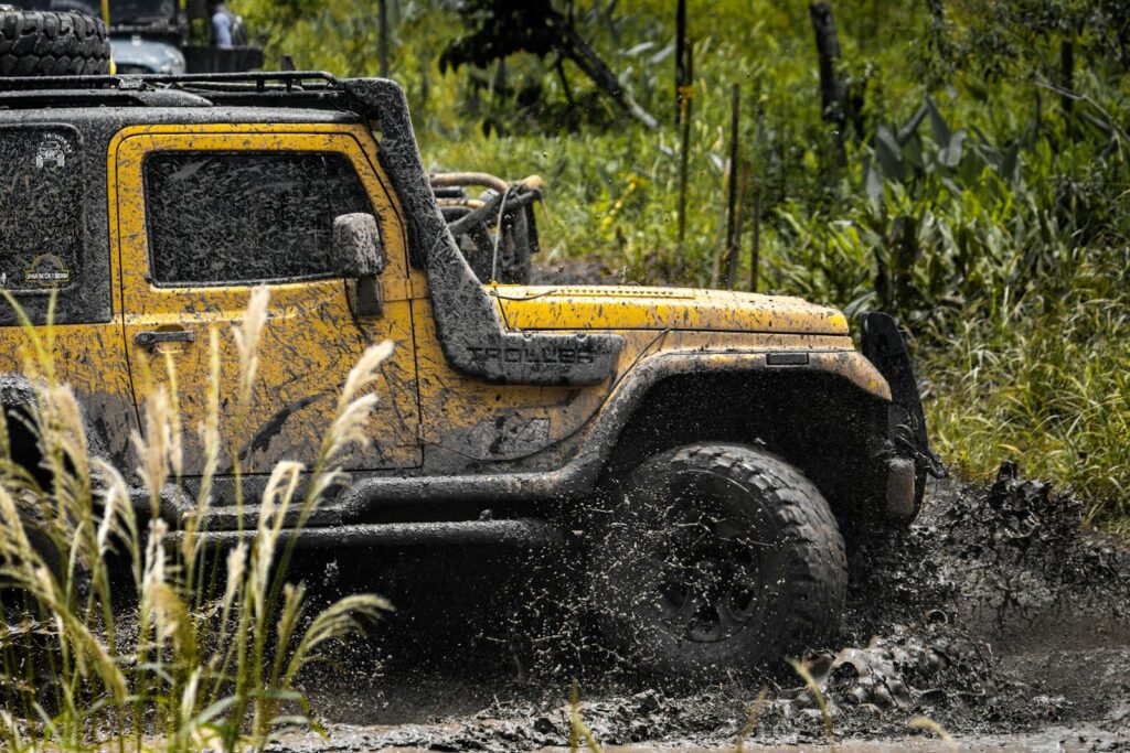 Yellow jeep conquering muddy terrain in an exciting off-road adventure.